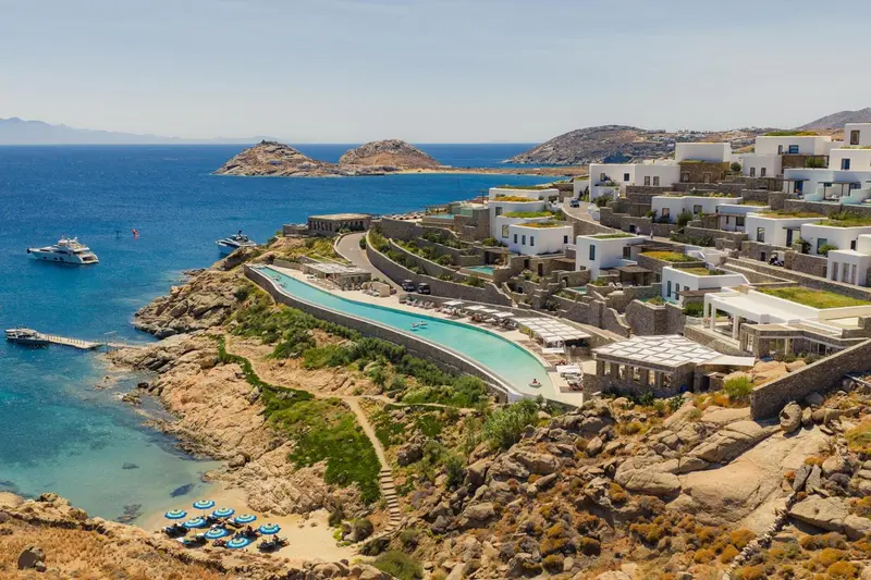 Vue aérienne d'un complexe hôtelier blanc surplombant une piscine et la mer.