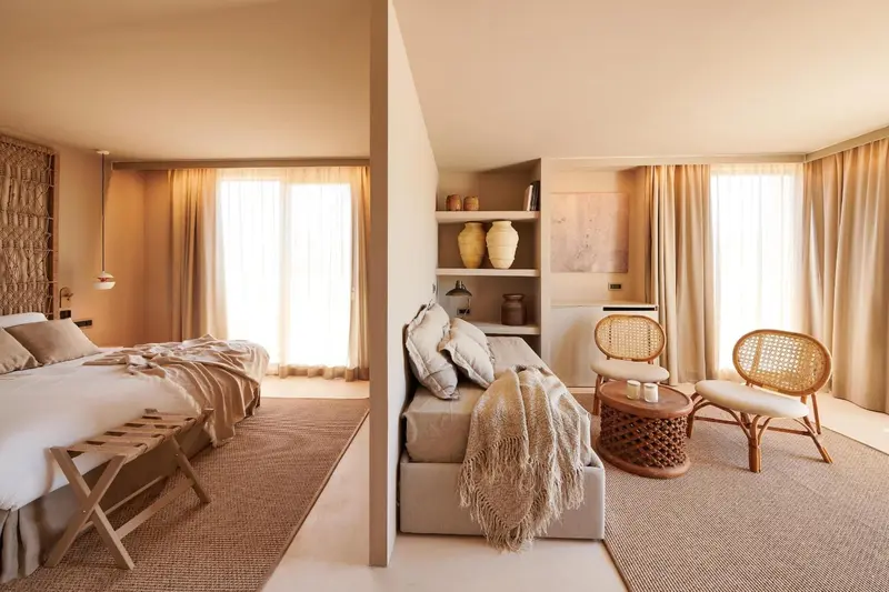 Espace de vie intérieur lumineux avec un lit et un coin salon.