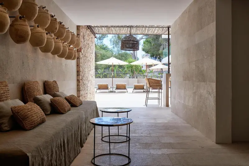 Espace de détente extérieur avec canapés et tables basses donnant sur une piscine et des parasols.