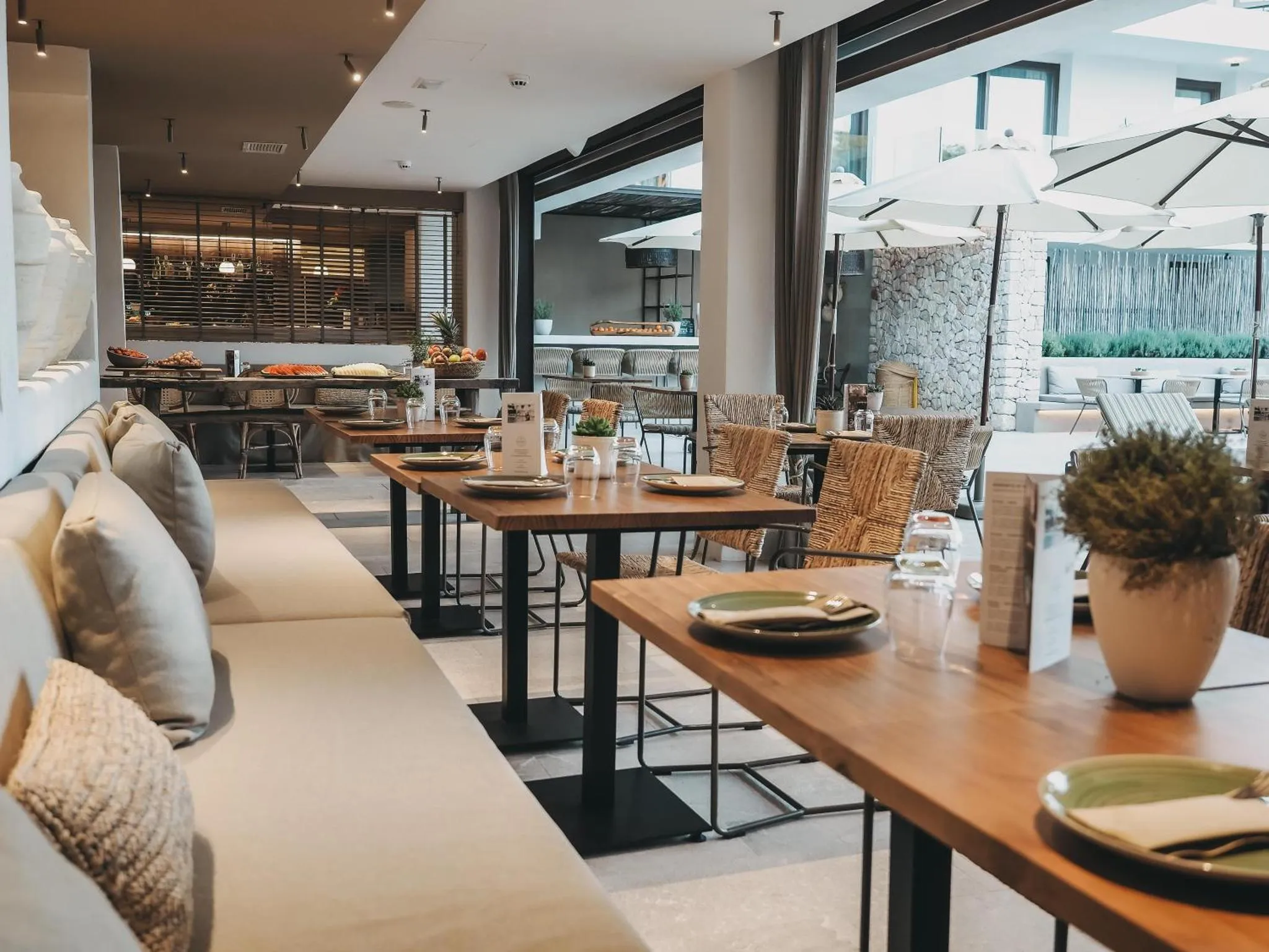 Une salle à manger lumineuse avec des tables dressées et des canapés confortables.