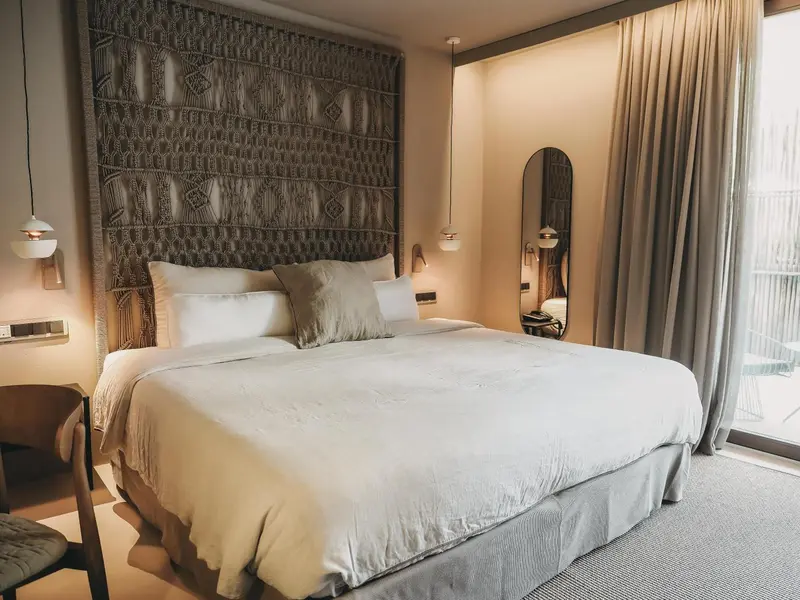 Une chambre lumineuse avec un grand lit recouvert de coussins et d'une couverture.
