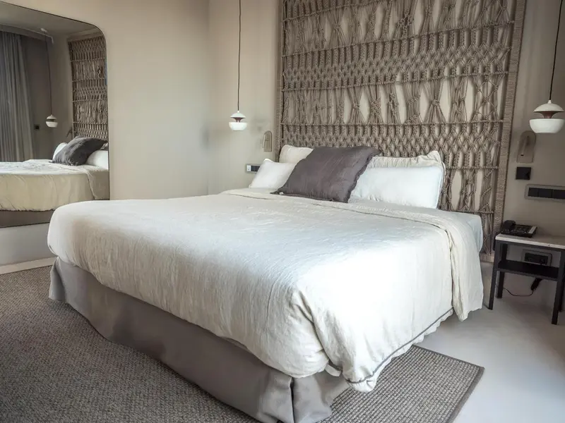 Une chambre lumineuse avec un grand lit et une décoration murale texturée.