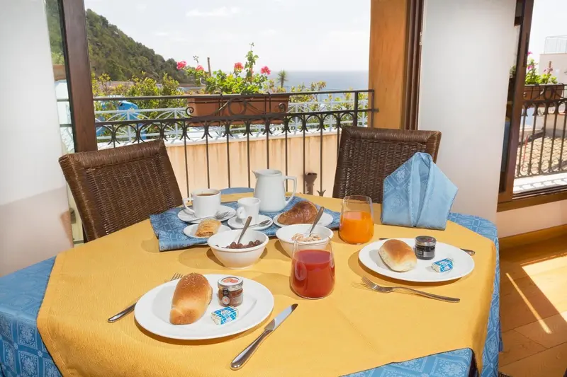 Une table est dressée pour le petit-déjeuner sur un balcon avec vue sur la mer.