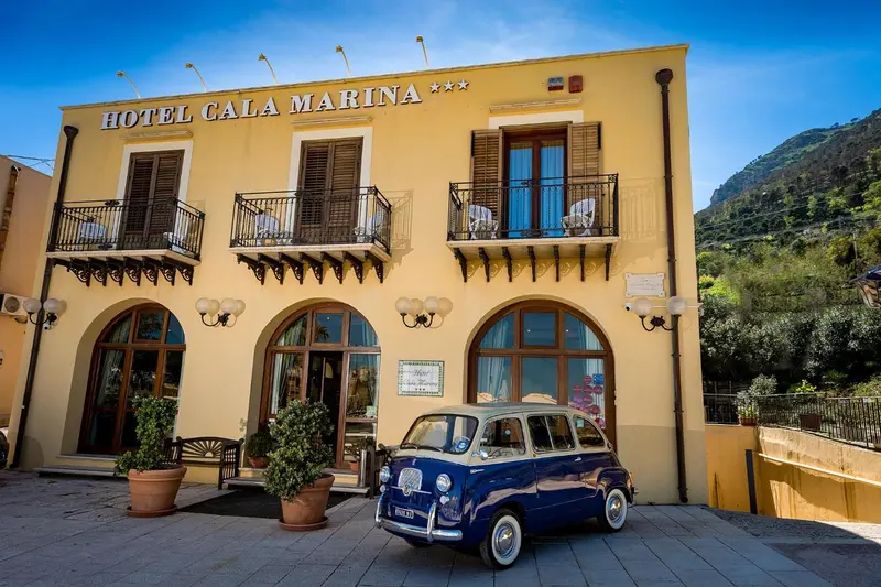 Façade jaune d'un hôtel avec des balcons et une voiture vintage devant.