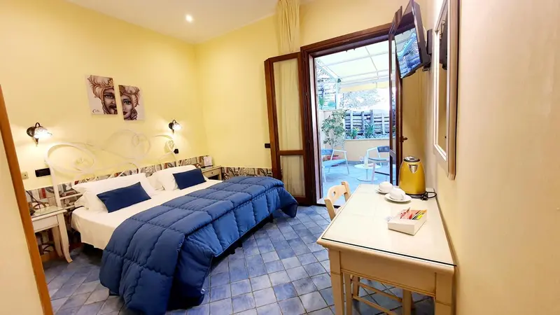 Une chambre lumineuse avec un lit double et un accès à une terrasse.