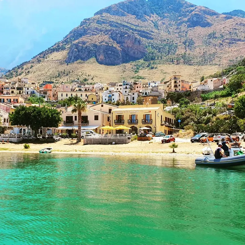 Vue d'une plage avec des bateaux amarrés devant un village et une montagne.