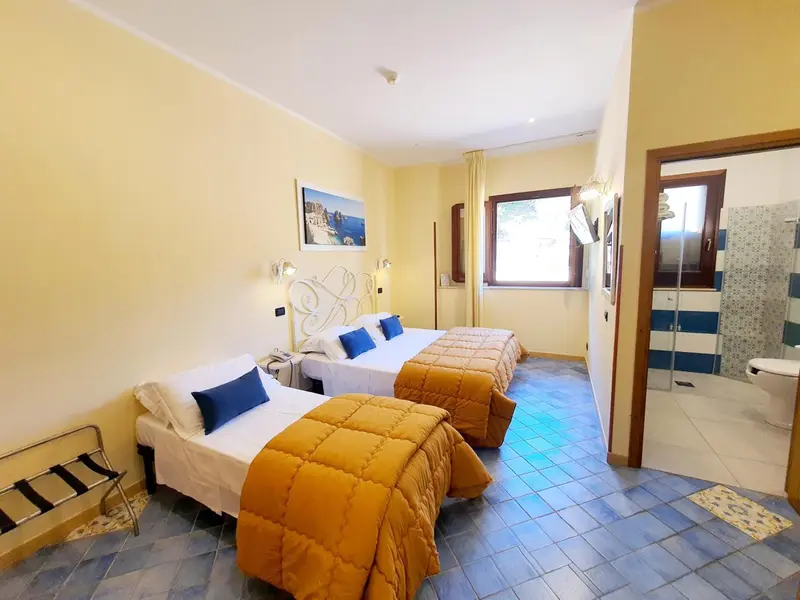 Une chambre lumineuse avec deux lits simples et une salle de bain.