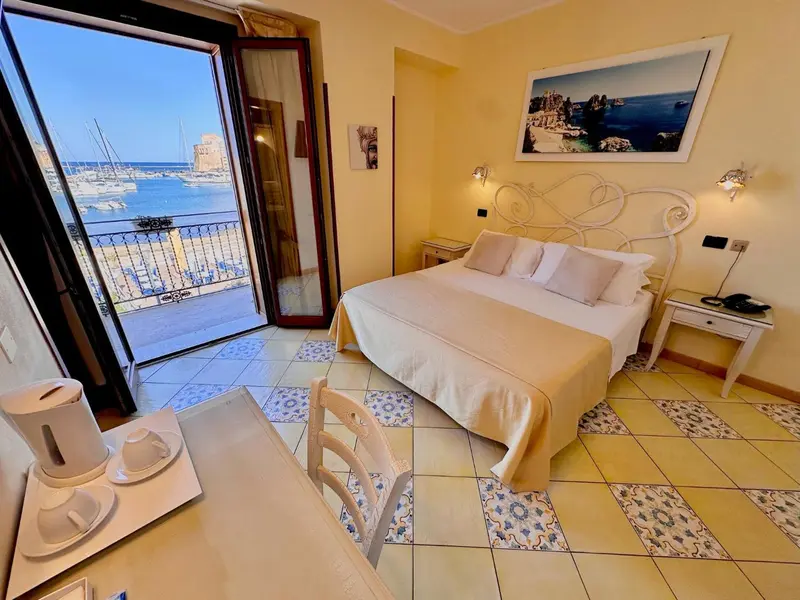 Chambre lumineuse avec vue sur un port de plaisance et une mer bleue.