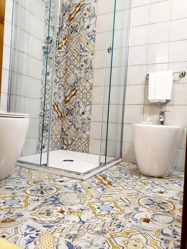 Une salle de bain lumineuse avec une douche à l'italienne aux motifs colorés.