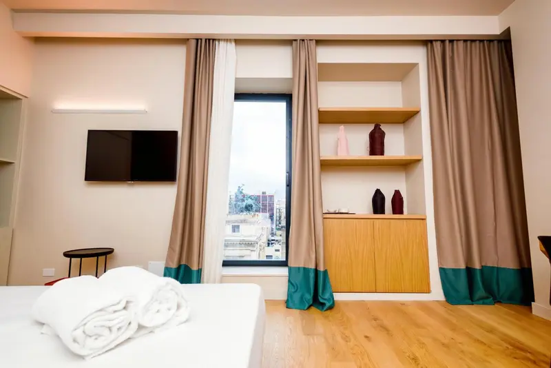 Une chambre lumineuse avec un lit et une vue sur la ville.