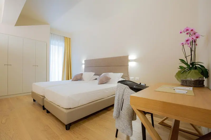 Une chambre lumineuse avec deux lits simples et un bureau en bois.