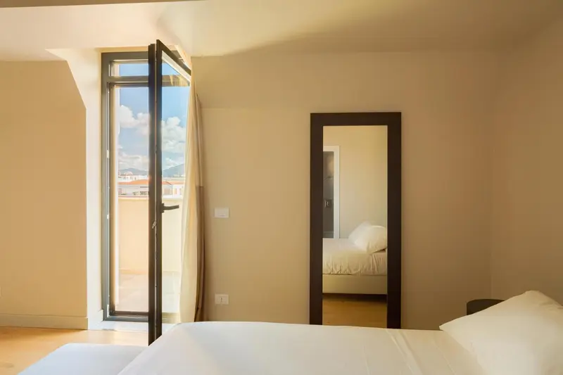 Une chambre lumineuse s'ouvre sur un balcon avec vue sur la ville.