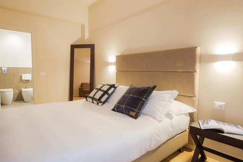Une chambre lumineuse avec un grand lit recouvert d'une courtepointe à carreaux.
