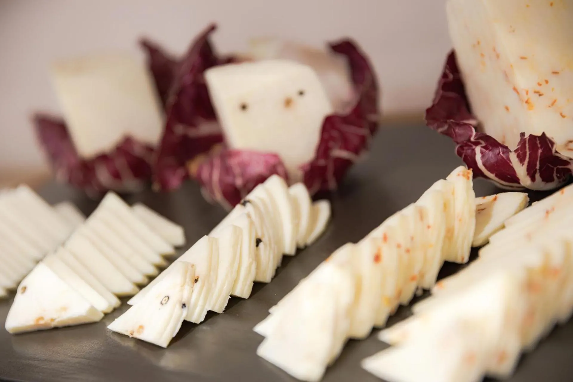 Assortiment de fromages et de crudités disposés sur une ardoise.