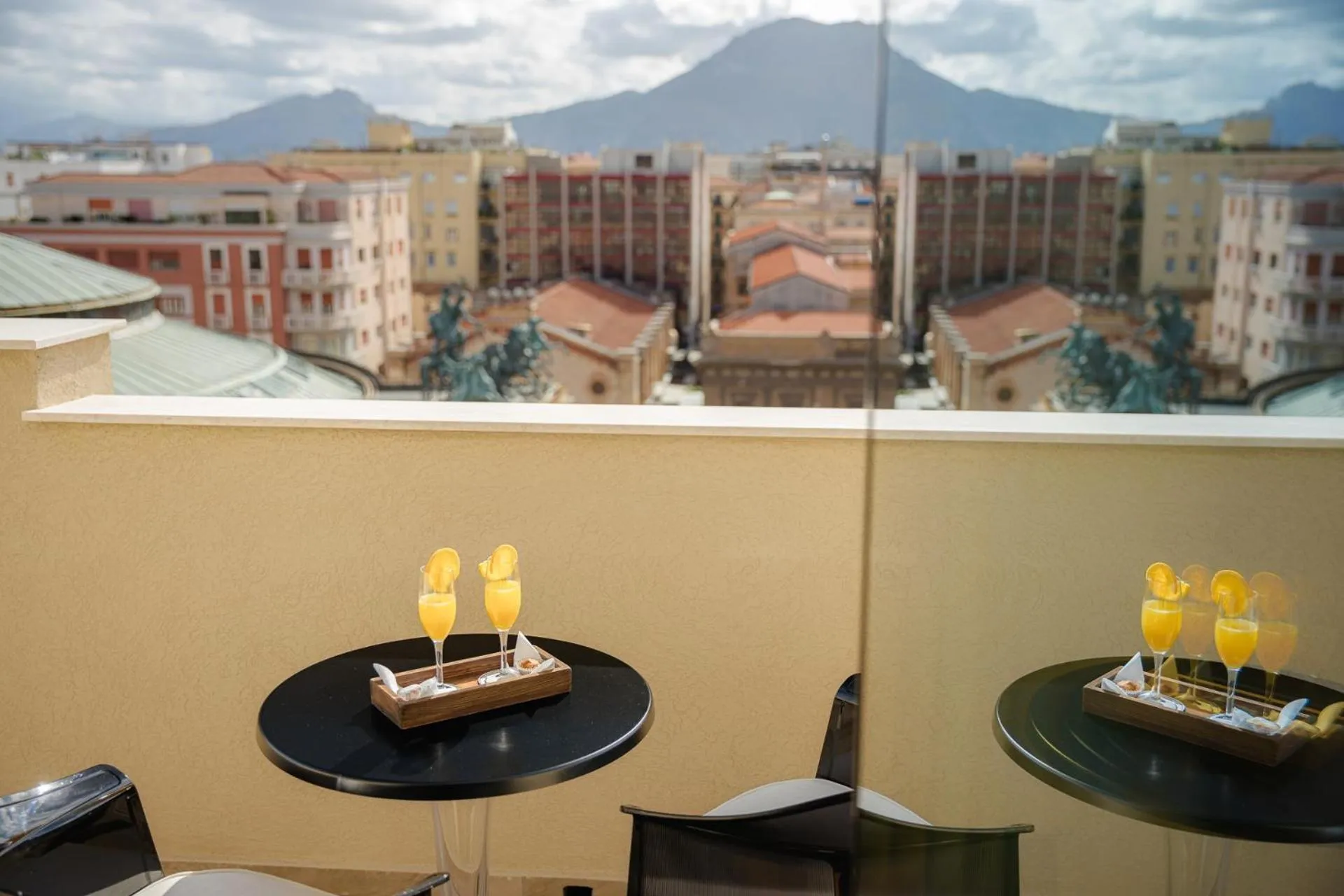 Deux tables avec des verres de jus d'orange sur une terrasse ensoleillée.