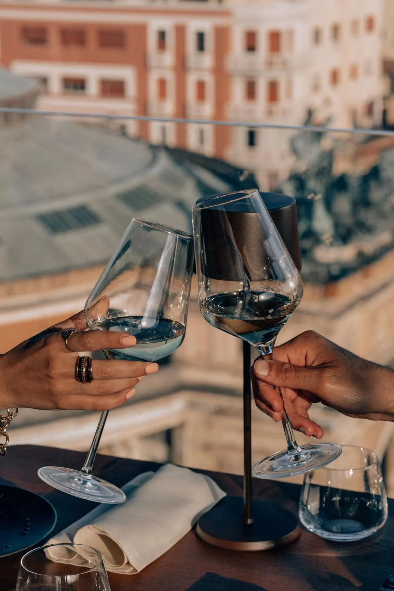 Deux personnes trinquent avec des verres de vin sur une terrasse.