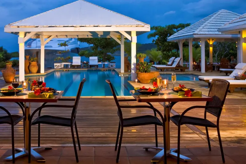 Table dressée au bord d'une piscine éclairée en soirée.