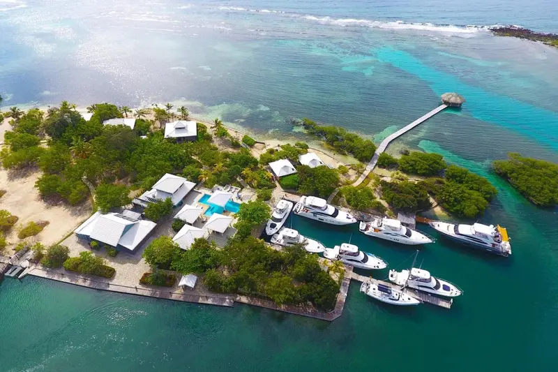 Vue aérienne d'un complexe hôtelier avec des bateaux amarrés et une plage.