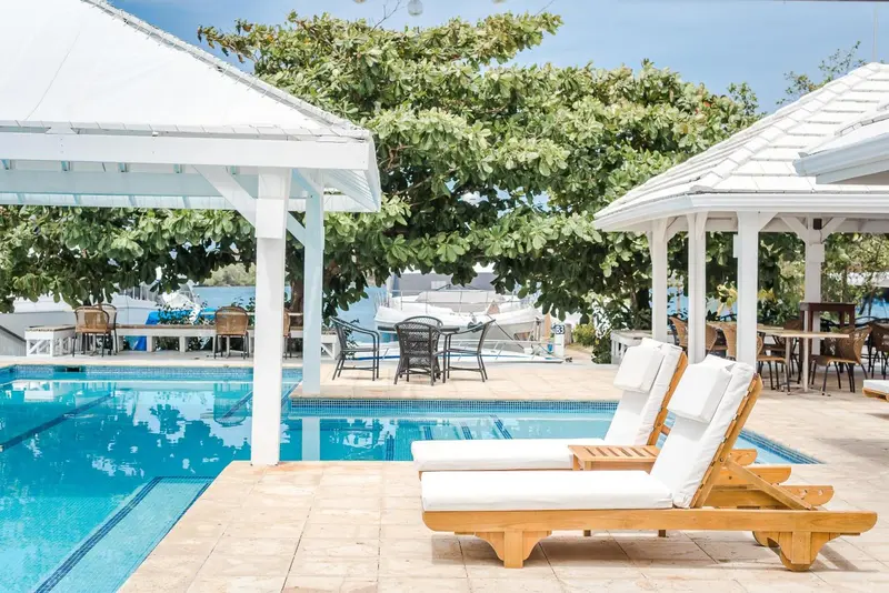 Transats et piscine ensoleillés sous des pergolas ombragées.