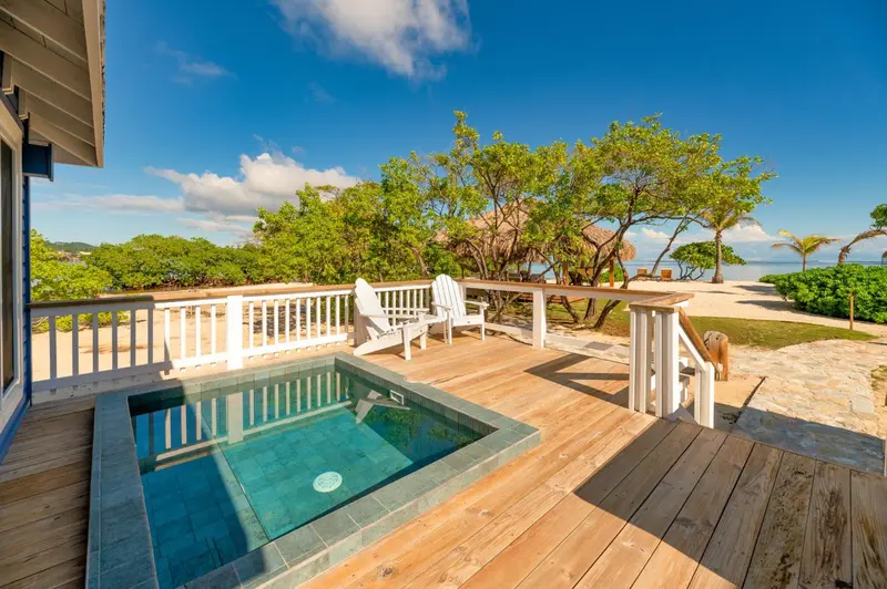 Terrasse en bois avec jacuzzi et mobilier de jardin face à la mer.