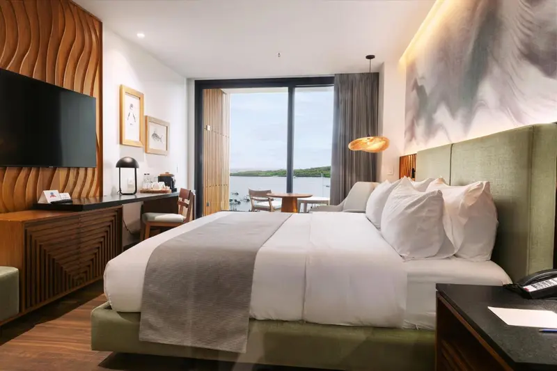 Une chambre lumineuse avec un grand lit et une vue sur l'océan.