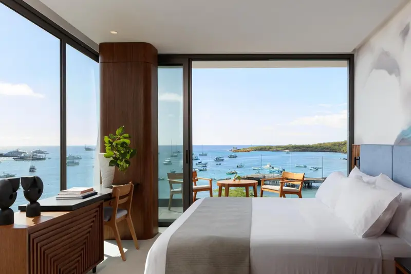 Une chambre lumineuse avec un grand lit donnant sur une vue mer et une terrasse.