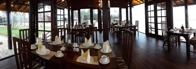 Une salle à manger lumineuse avec des tables dressées pour le service.