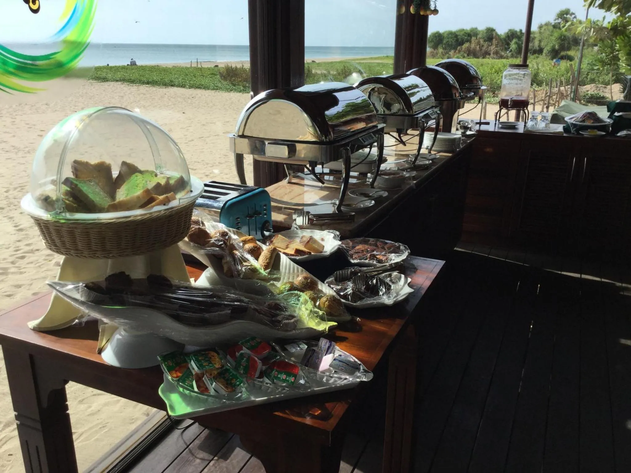 Un buffet propose des viennoiseries et des plats chauds sur une table en bois.