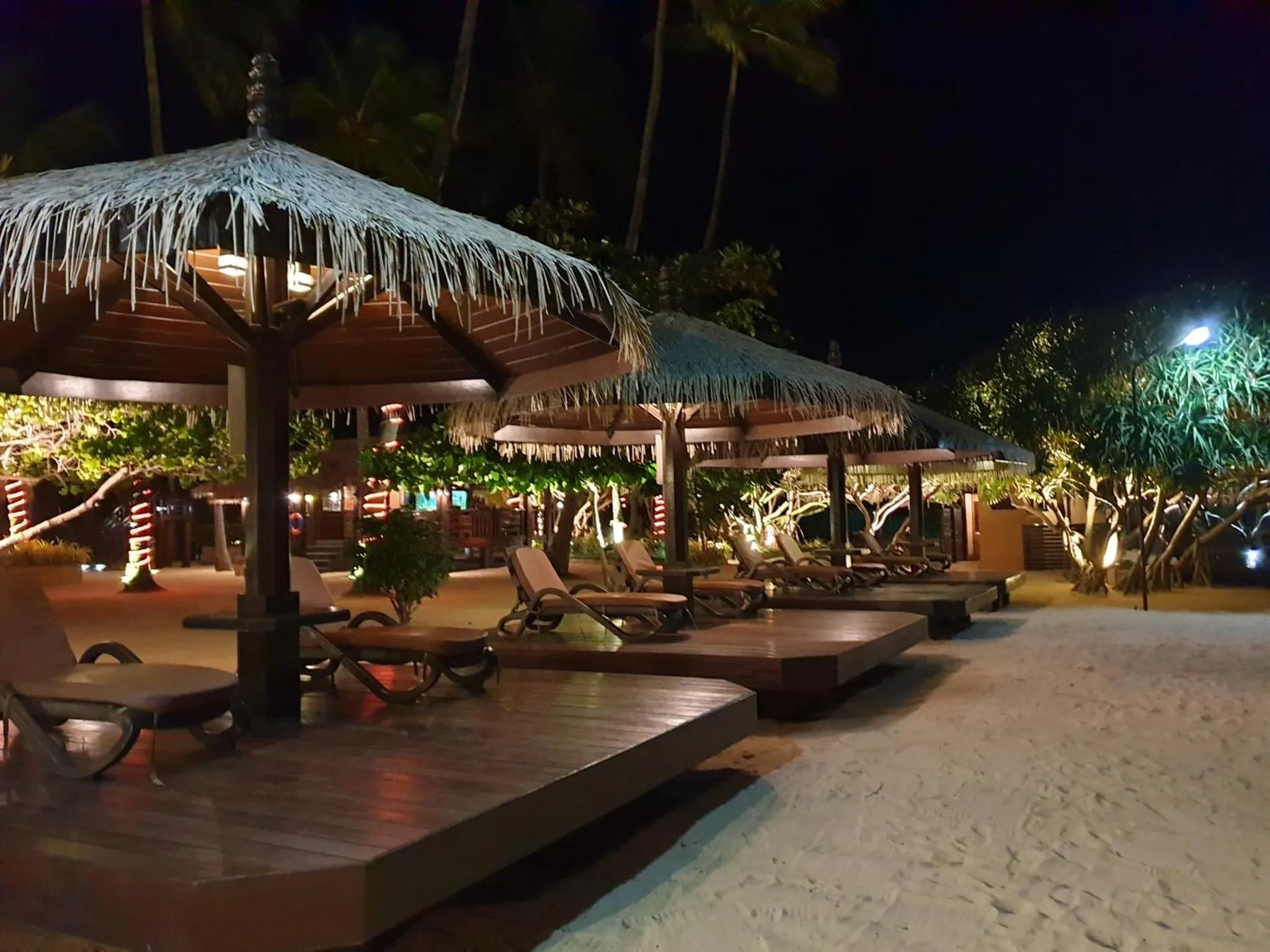 Terrasse lumineuse avec mobilier de détente sur une plage de sable.