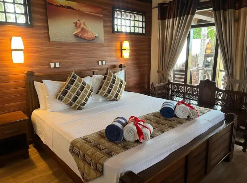 Une chambre avec un grand lit décoré de coussins et de serviettes roulées.
