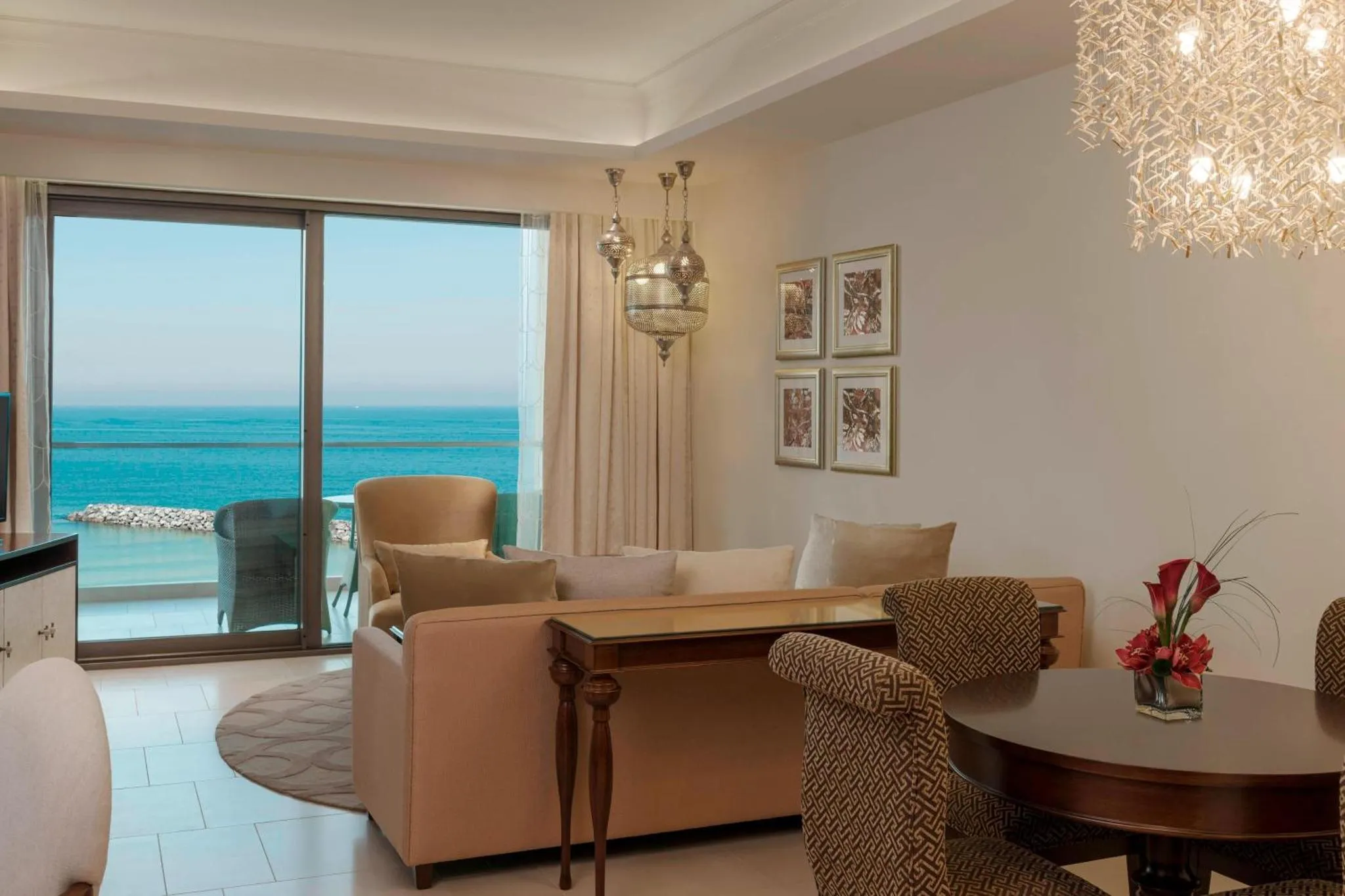 Espace de détente lumineux avec canapés et table basse face à une baie vitrée donnant sur la mer.