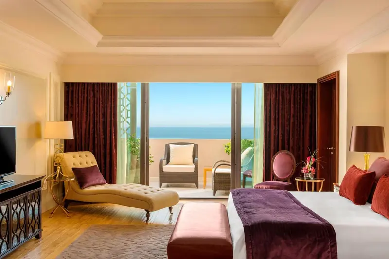 Une chambre lumineuse avec un lit et un accès à un balcon offrant une vue sur la mer.