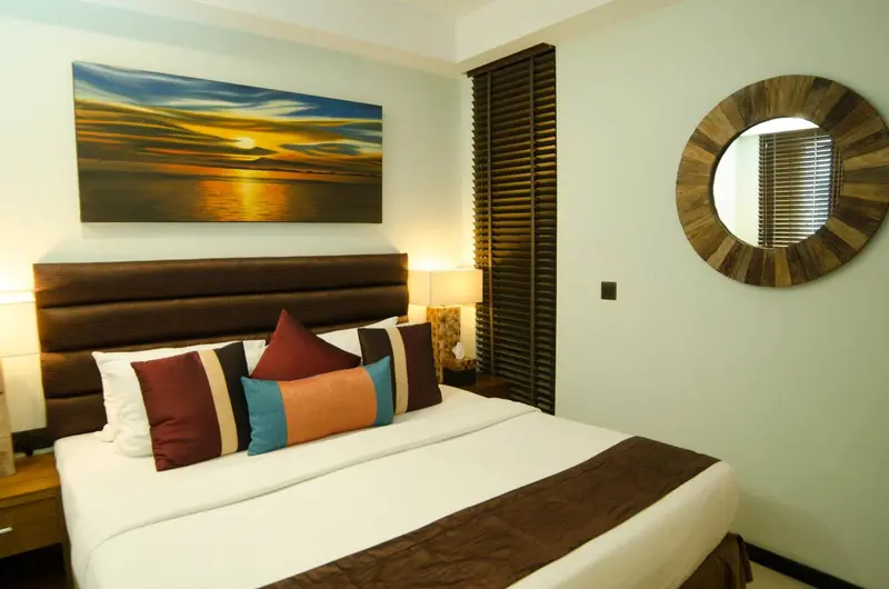 Une chambre lumineuse avec un grand lit recouvert d'une courtepointe et de coussins décoratifs.