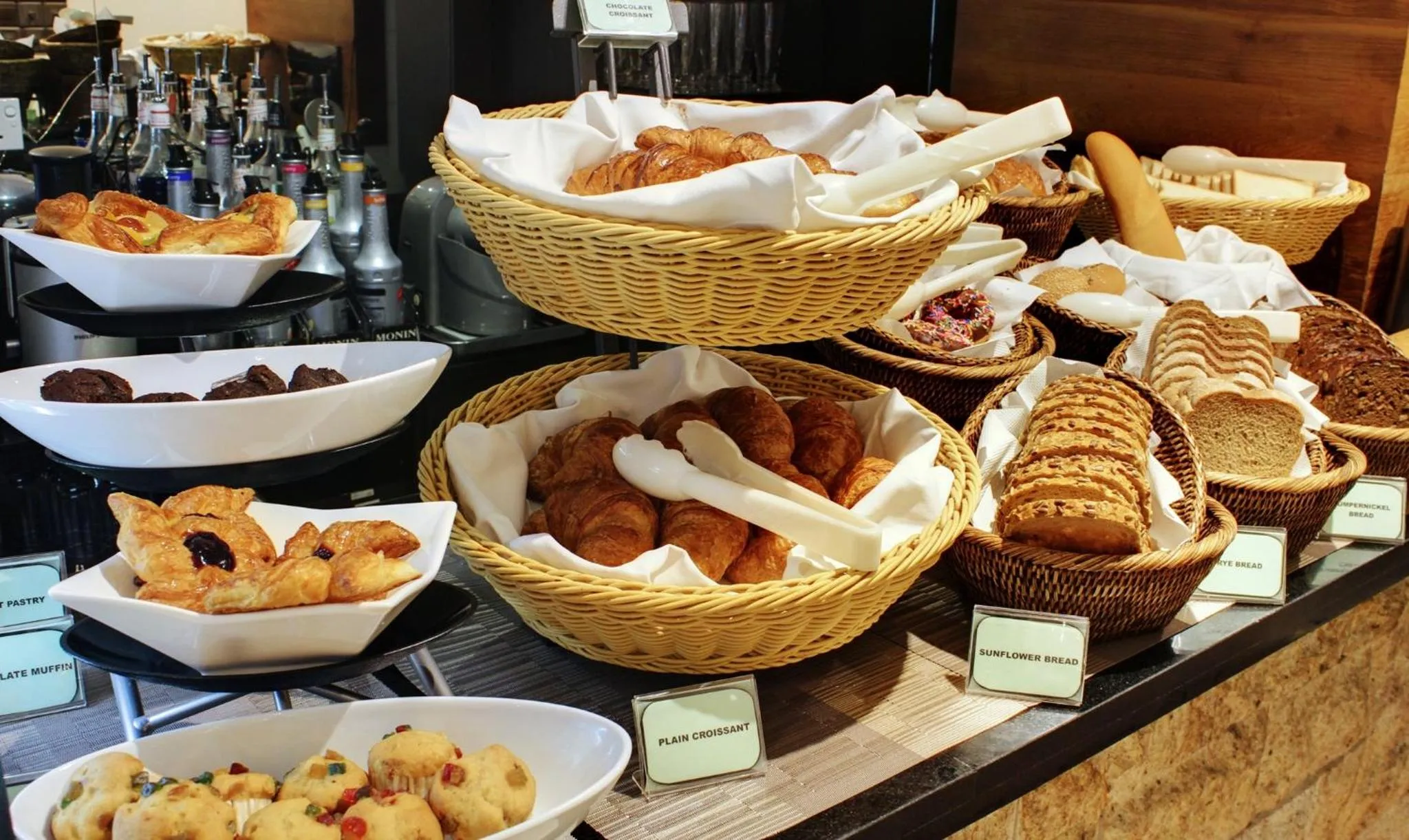 Présentation de viennoiseries et de pains variés sur un buffet.