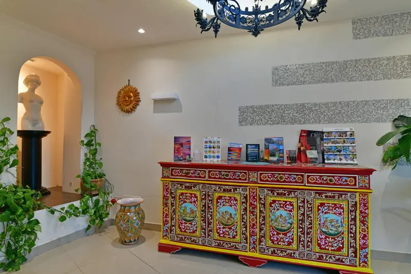 Un comptoir d'accueil décoré se trouve dans un hall lumineux avec des plantes et des œuvres d'art.