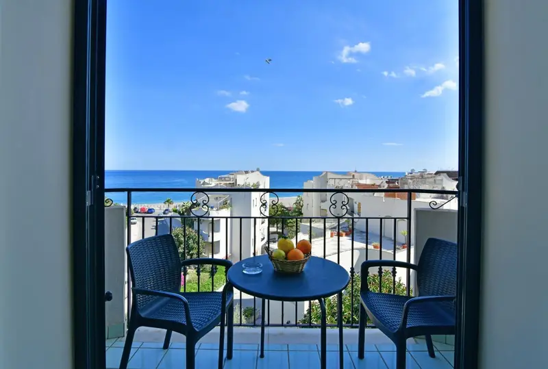 Vue sur la mer depuis une terrasse aménagée avec table et chaises.