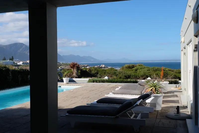 Terrasse avec transats et piscine donnant sur un paysage côtier.