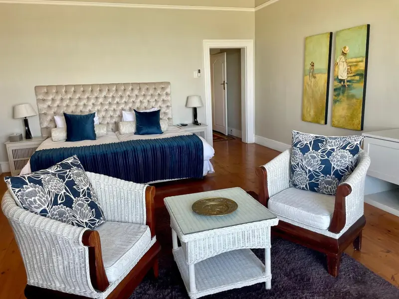 Une chambre lumineuse avec un grand lit et deux fauteuils.