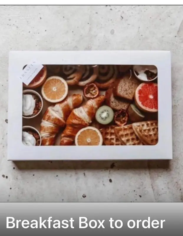Assortiment de viennoiseries, fruits et gaufres présentés dans une boîte.