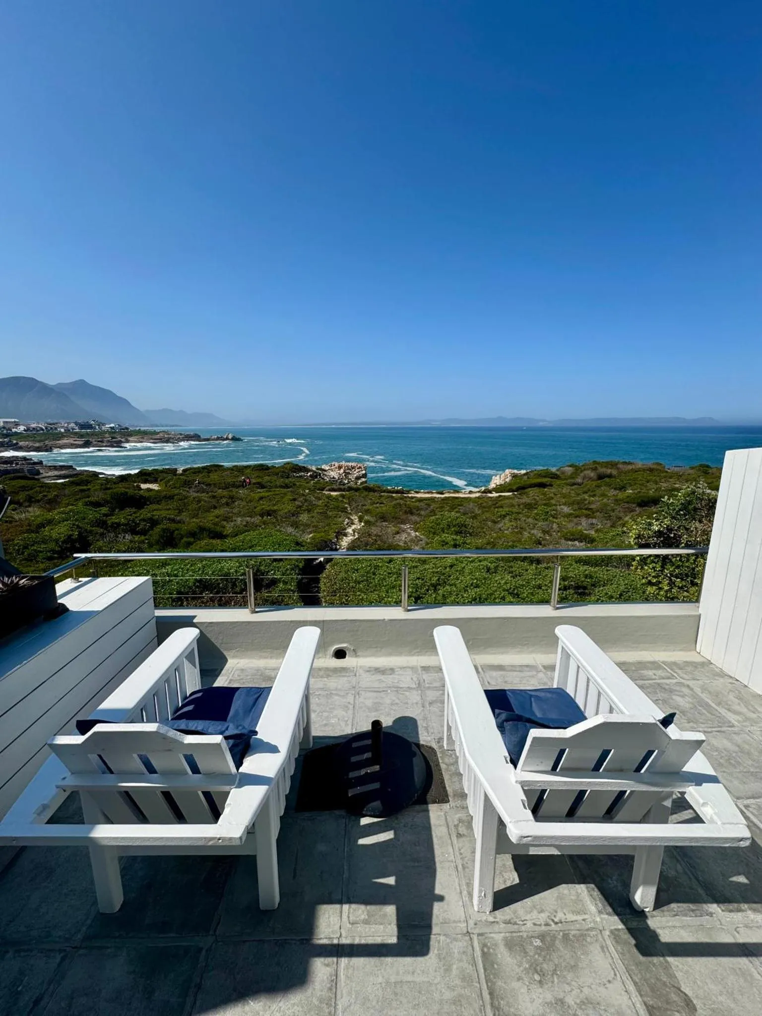 Deux chaises longues blanches invitent à la détente sur une terrasse ensoleillée avec vue sur la mer.