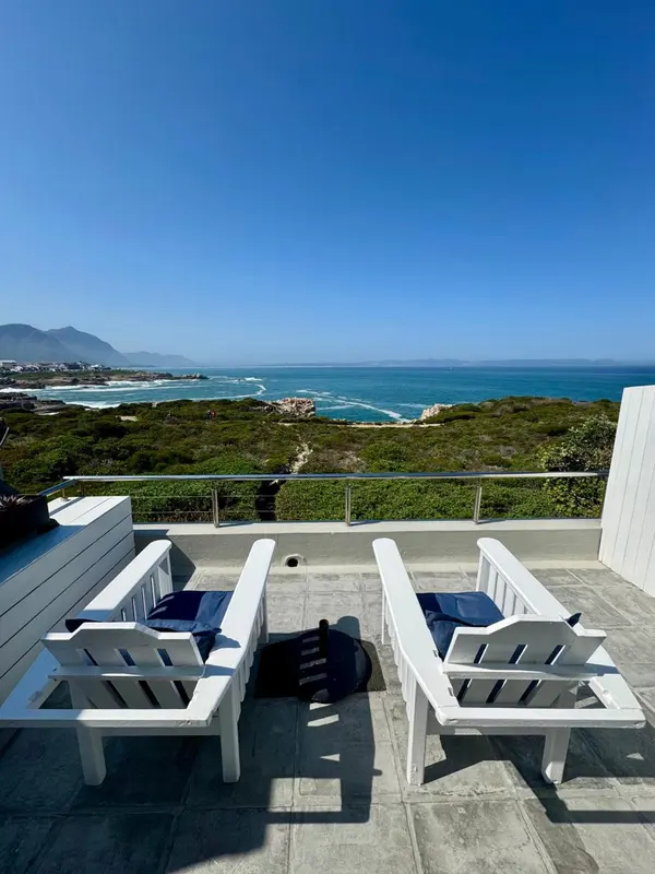 Deux chaises longues blanches invitent à la détente sur une terrasse ensoleillée avec vue sur la mer.