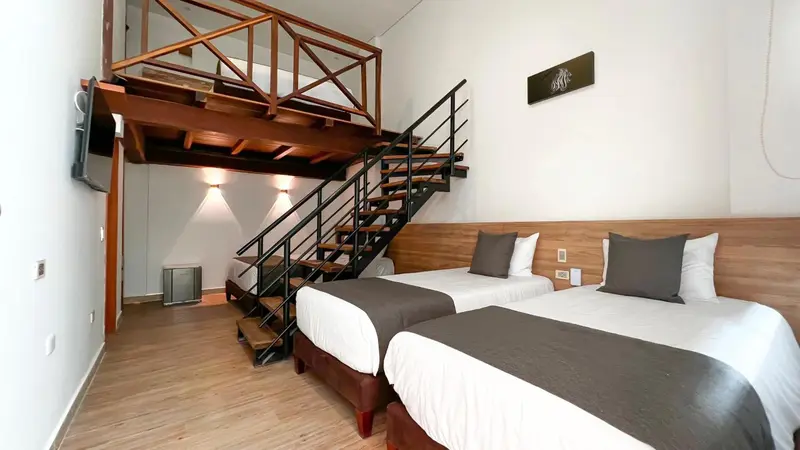 Une chambre avec deux lits simples et une mezzanine en bois.