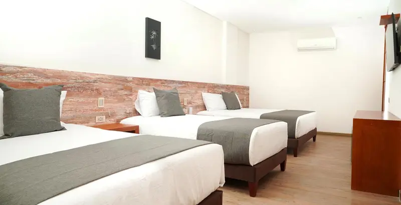 Chambre avec trois lits simples et un mur texturé.