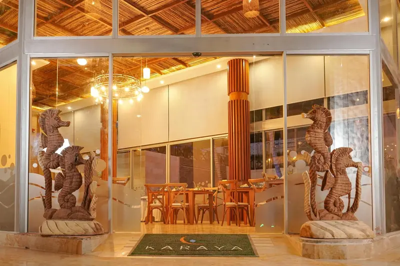 Hall d'entrée lumineux avec des sculptures d'hippocampes et des tables.