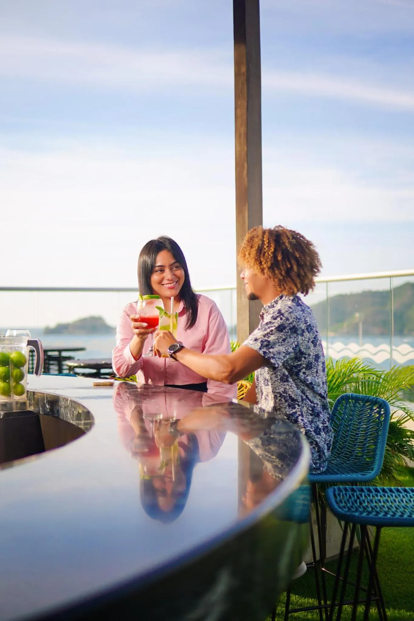 Un couple discute autour d'un bar avec vue sur la mer.