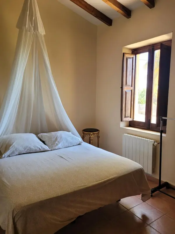 Une chambre lumineuse avec un lit à baldaquin et une fenêtre.