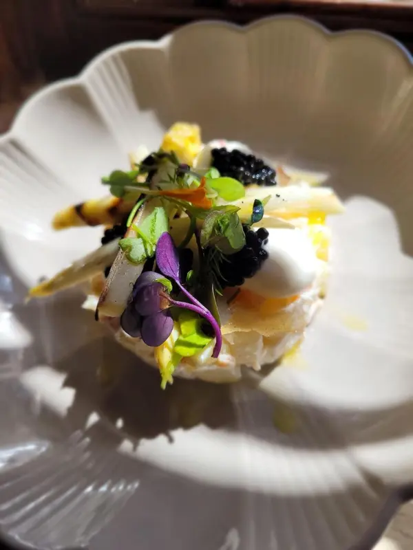 Assiette raffinée ornée de caviar, de légumes verts et d'une préparation à base de poisson.