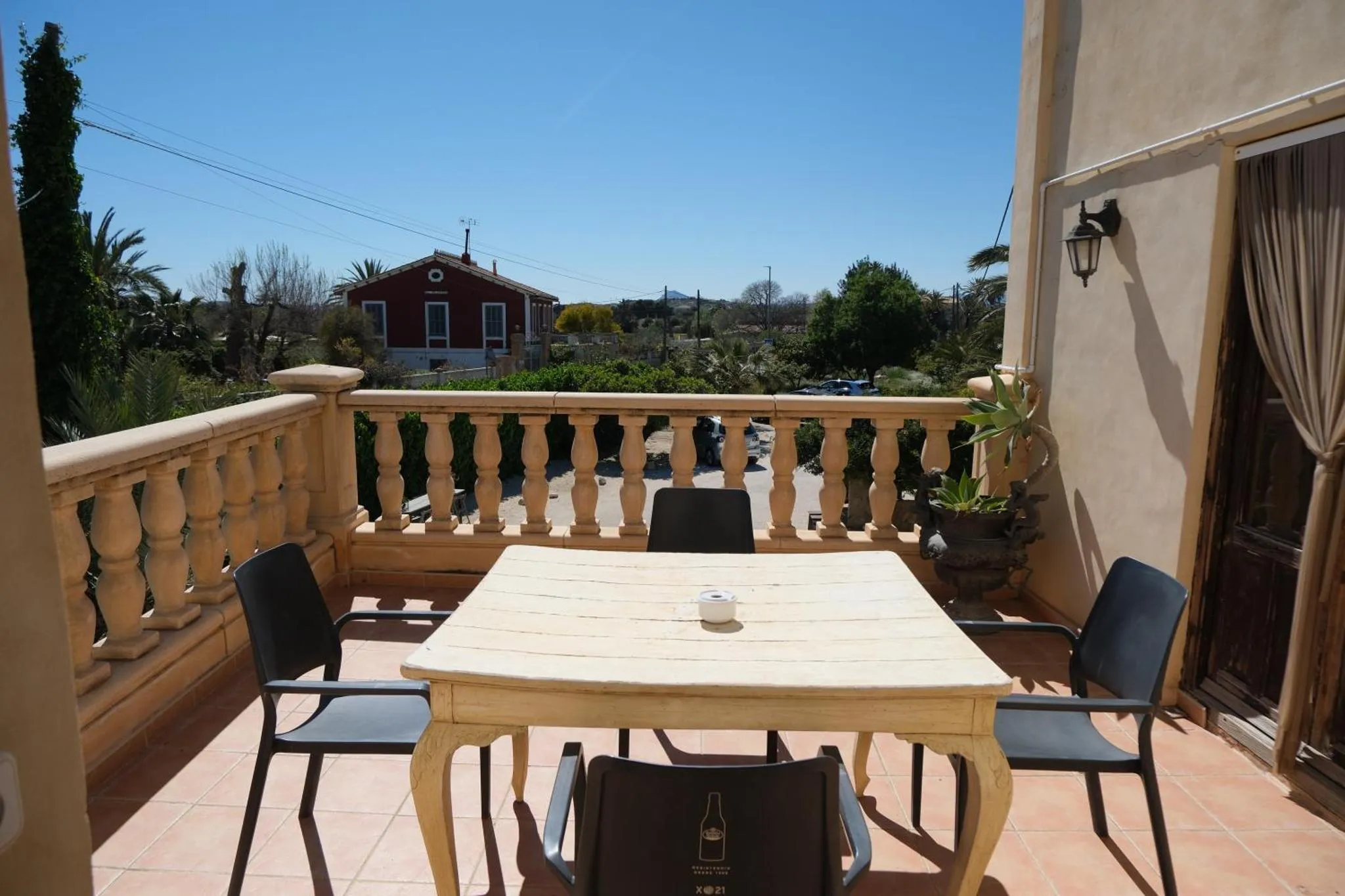 Une table et des chaises sont disposées sur une terrasse carrelée avec vue sur un paysage verdoyant.
