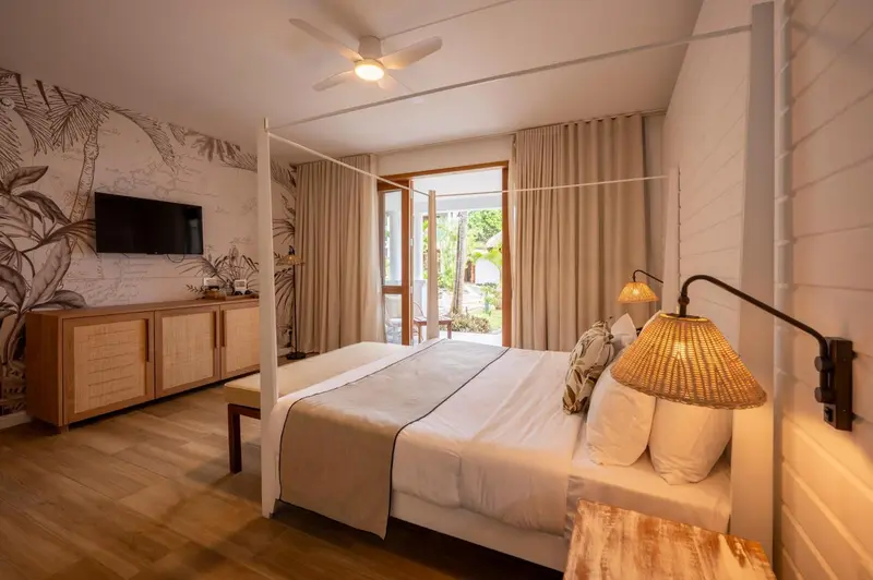 Une chambre lumineuse avec un grand lit à baldaquin et une décoration tropicale.
