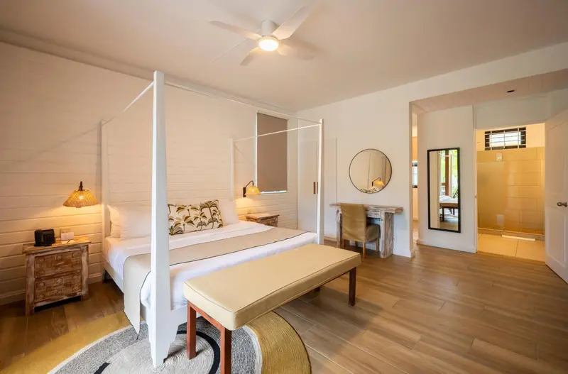 Une chambre lumineuse avec un lit à baldaquin et une décoration sobre.